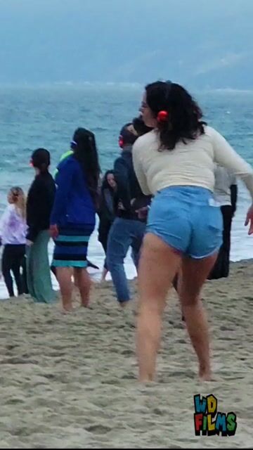 Woman dancing on beach in top and shorts, fully clothed