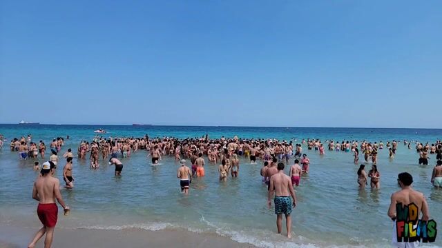 Water wrestling in bikinis, clothed physical play, public beach, not sexualized