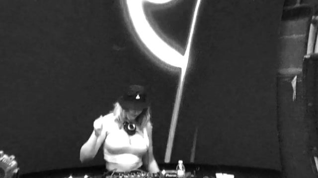 Female DJ performing on stage, fully clothed