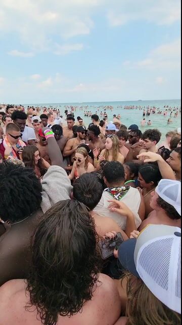 Large beach crowd in normal swimwear; party context