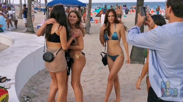 Beach groups in swimwear posing for cameras, normal beach context
